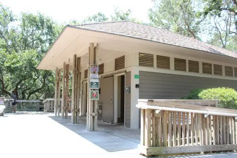 Restroom building with a wide roof overhang among trees