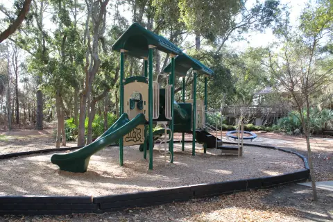 Playground with slides on a wood-chip surface among trees