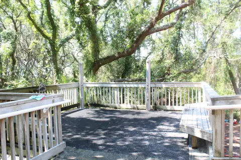 Wooden overlook deck with railing and benches among oak trees