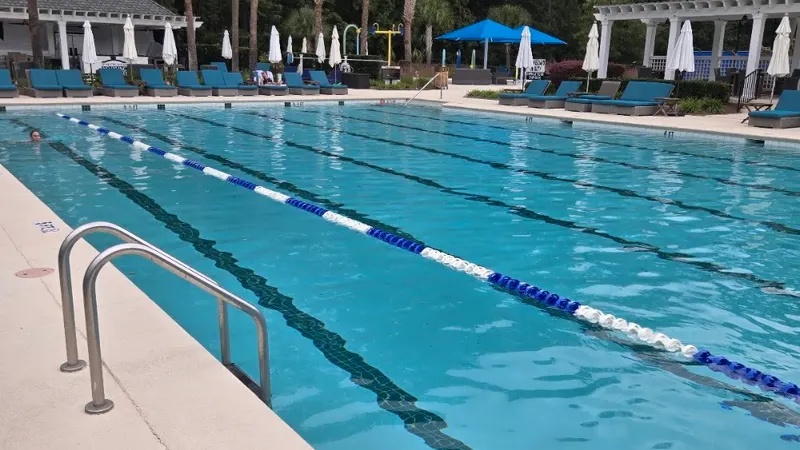 The lap pool at Belfair’s Sports & Lifestyle Campus, with lounge chairs and a pergola beyond
