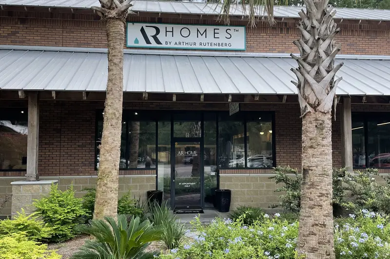 The AR Homes office, a brick and glass storefront behind palms and a planted bed