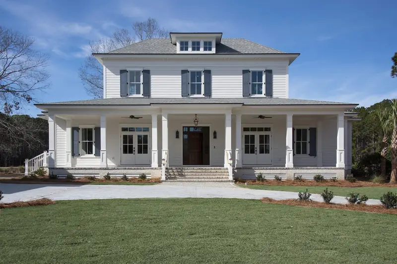 A white two-story house with a full-width front porch and dark shutters