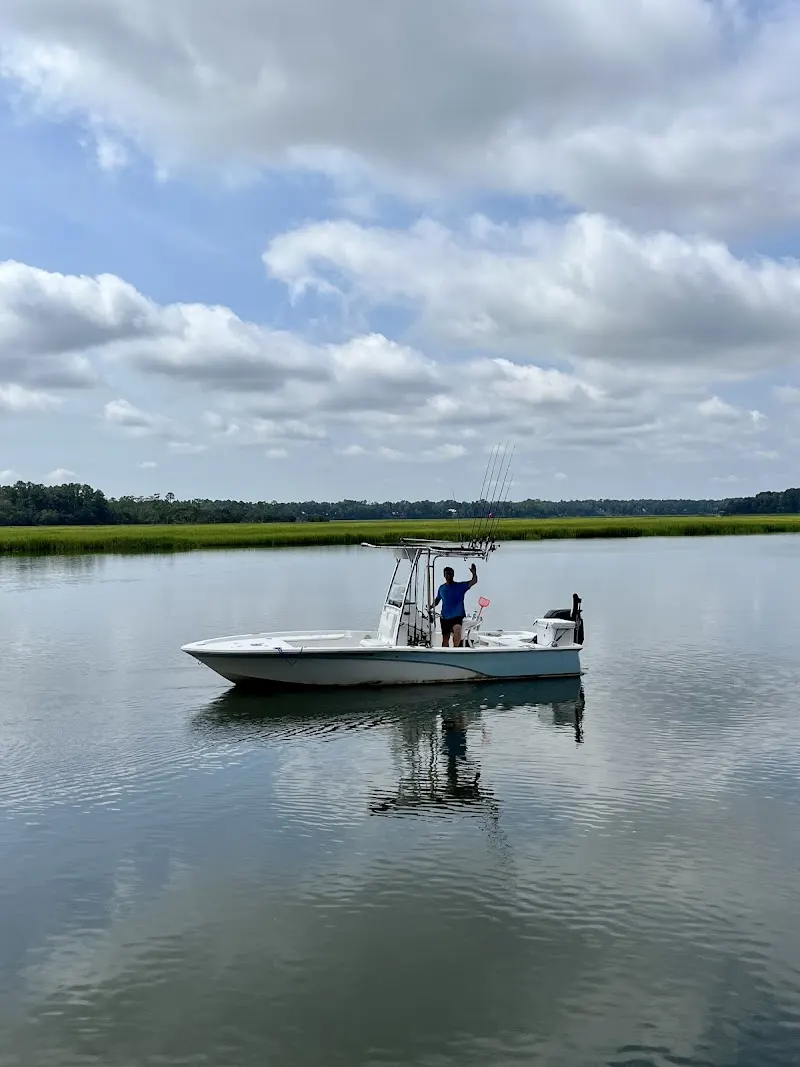 A small center-console fishing boat anchored in a calm May River creek with marsh grass behind