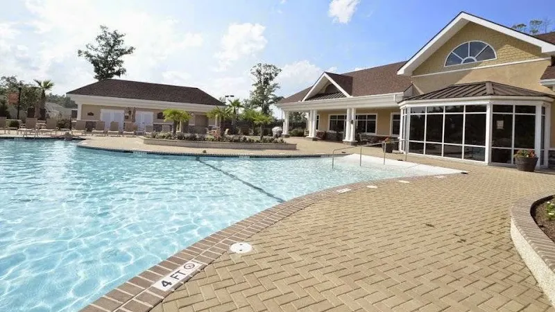 Swimming pool with lounge chairs in front of a clubhouse
