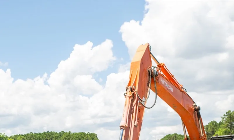An excavator against a summer sky at the Livewell Terrace site on Buckwalter Parkway, at the June 2026 groundbreaking