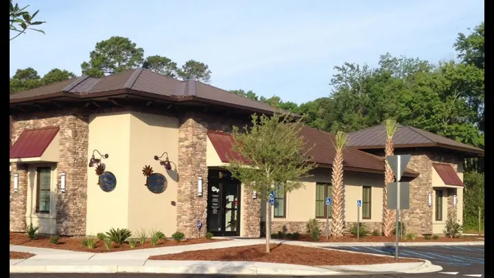 The stone and stucco Palmetto Medical Group building on Bluffton Parkway, with a red metal roof and palms by the entrance