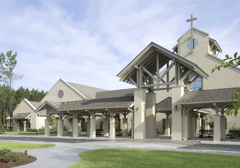The St. Gregory the Great buildings in Bluffton, with a cross on the bell tower above a covered entrance