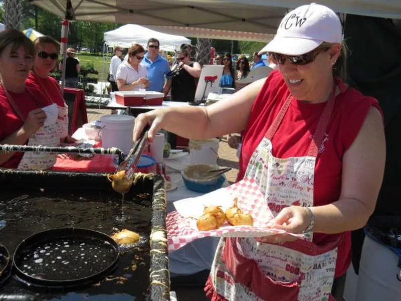 A vendor serving fried food from a fryer under the tents at Taste of Bluffton
