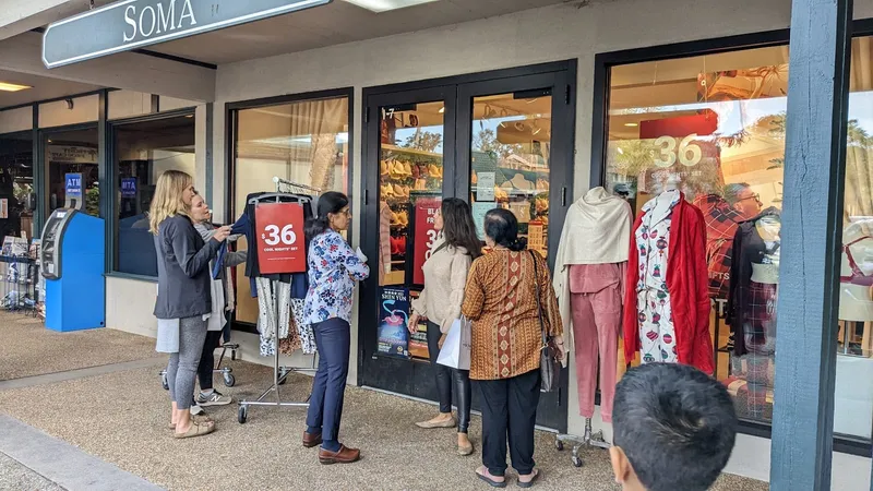 Shoppers browsing a clothing rack outside a storefront on the covered walkway at Coligny Plaza