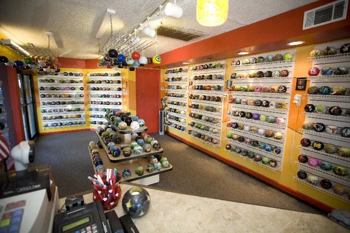 Wall shelves at Wax & Beyond in Coligny Plaza lined with round carved candles in sports-team logos and cartoon designs