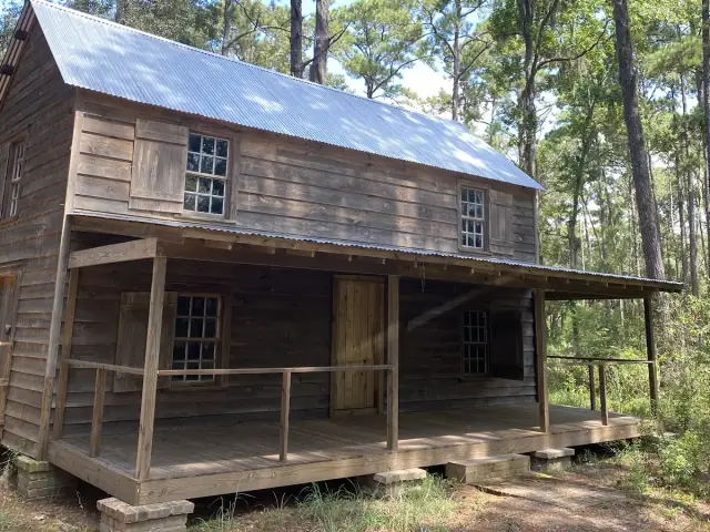 A weathered two-story wooden house with a tin roof and a deep front porch among the pines on Daufuskie Island