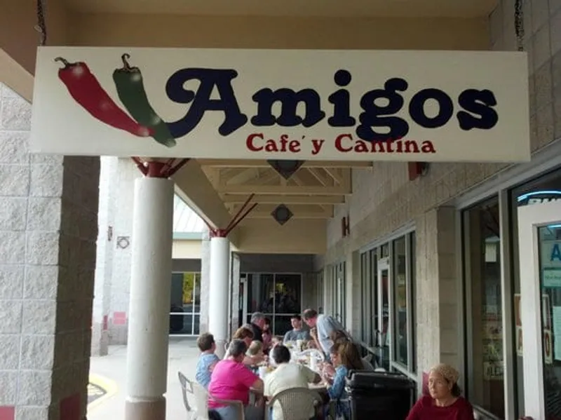 The Amigos Cafe y Cantina sign over the covered walkway, with diners seated outside