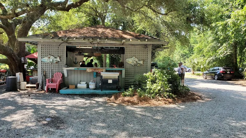 Barnacle Bill's open-air seafood market stand under live oaks on a gravel lot
