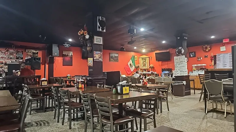 Dining room at Cabritos Mexican Restaurant with orange walls, wooden tables and a Mexican flag