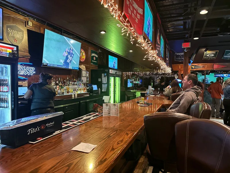 Long wooden bar at CocoNutz Sportz Bar with TVs and string lights overhead