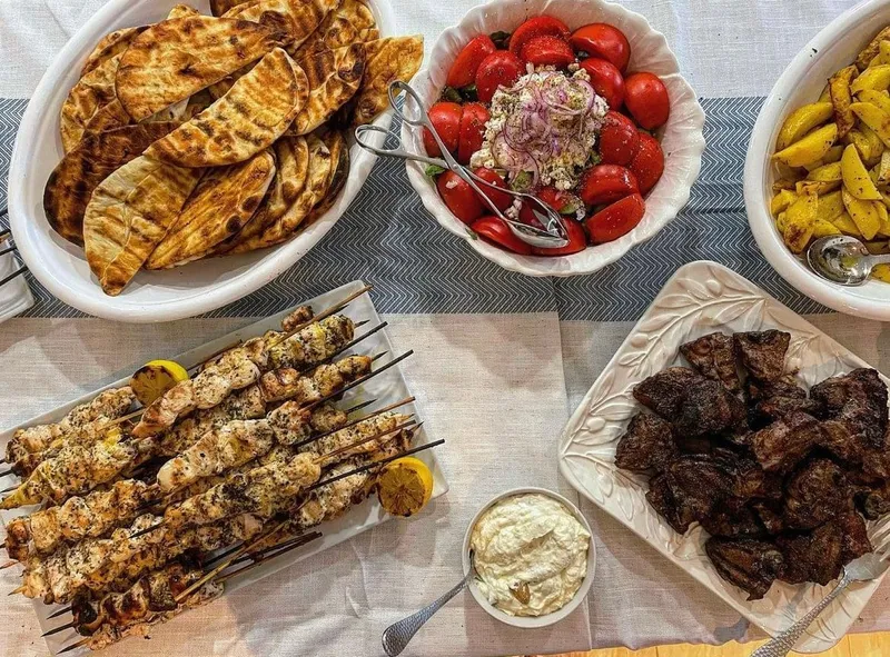 Family-style spread from Full Plate Catering: grilled flatbread, chicken skewers, steak tips and tomato salad