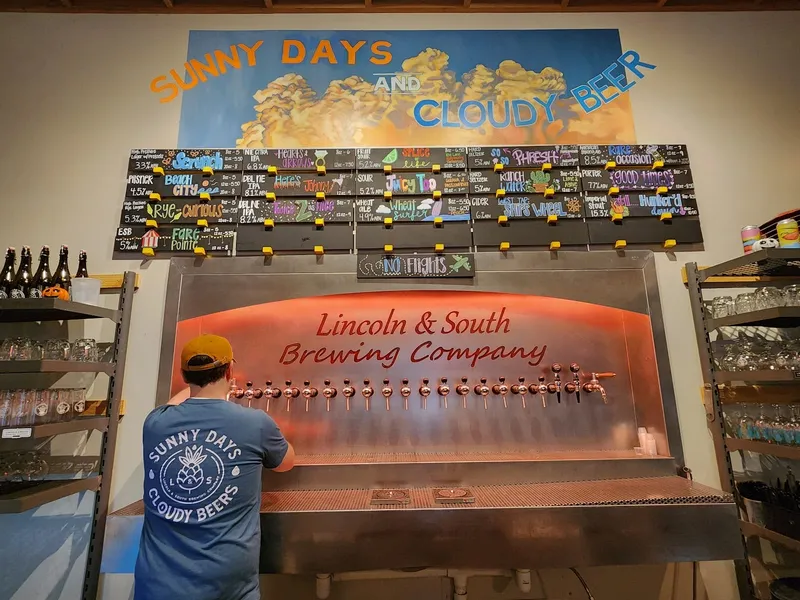 The tap wall at Lincoln and South Brewing Company, with the brewery name on the glowing tap board and a chalkboard beer list above