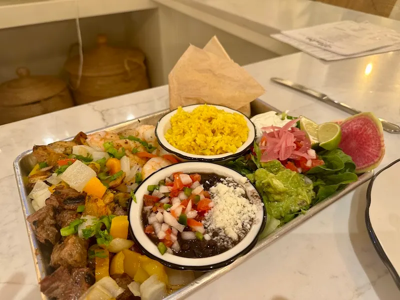 A tray of grilled meats, yellow rice, beans and salsa served at Madre Social Kitchen & Bar on Hilton Head