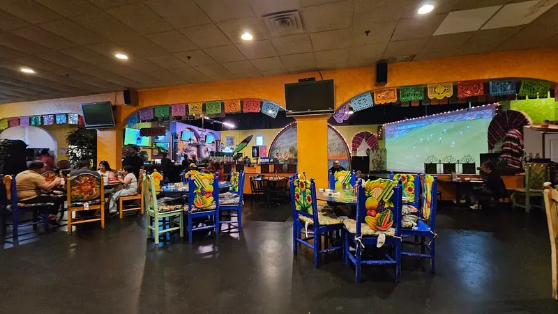 The colorful dining room at Mi Tierra Mexican Restaurant with painted chairs and papel picado banners