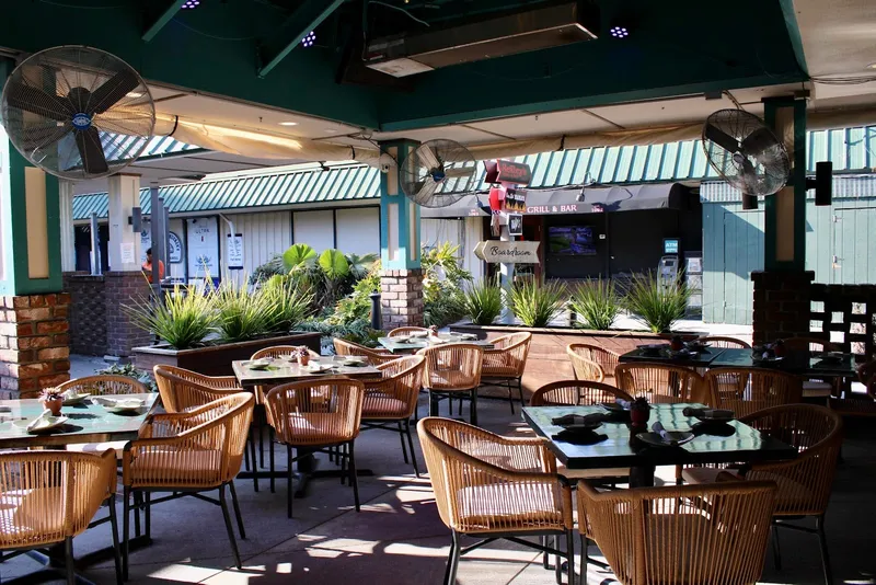 Covered patio dining area at Papi Tequila with tables, rattan chairs and ceiling fans