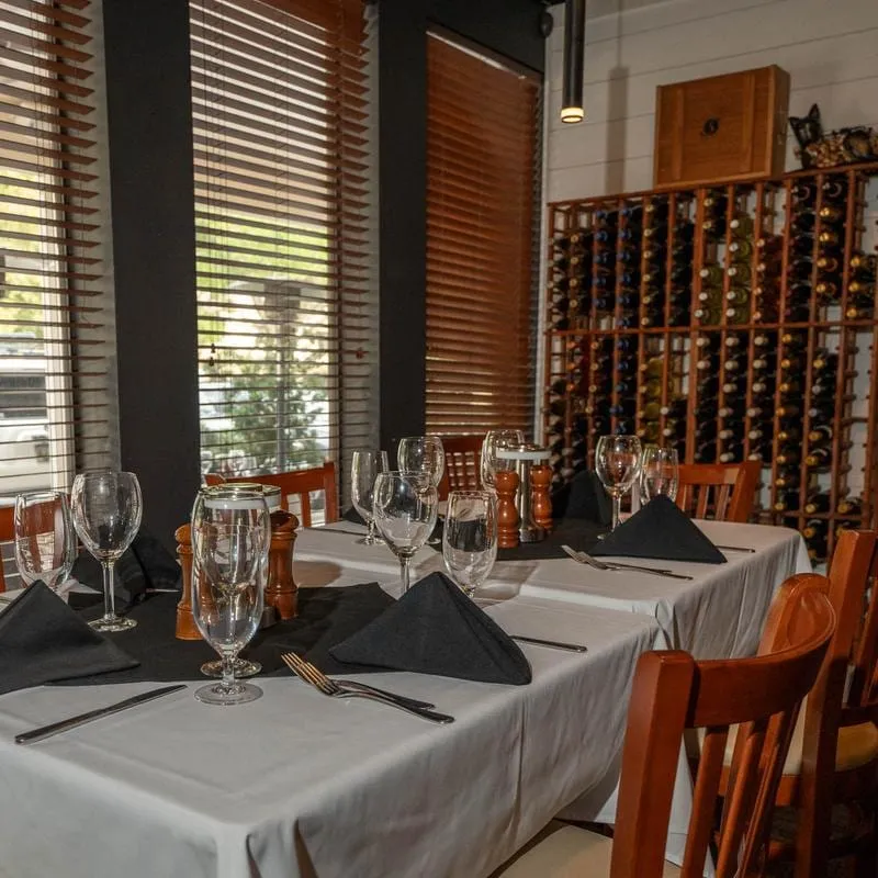 A set table in the Sage Room dining room, with wine bottles racked on the wall behind