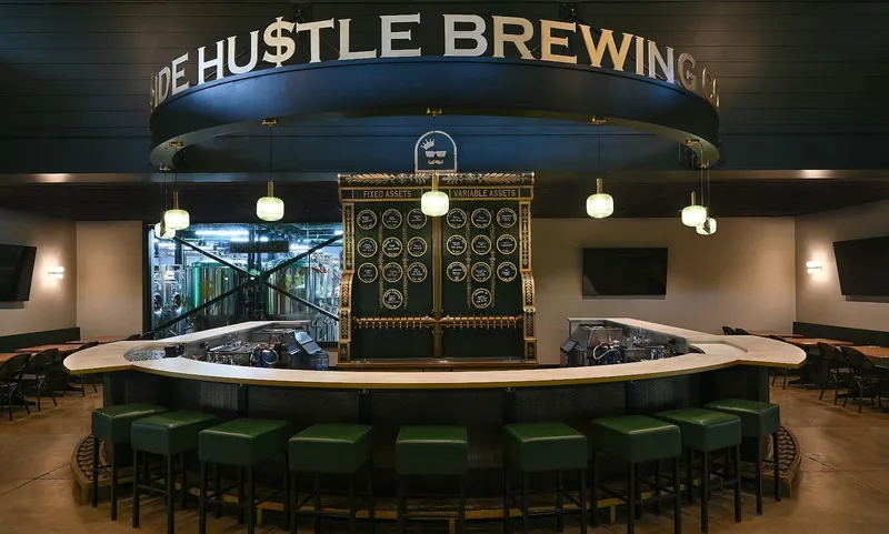 The round bar at Side Hustle Brewing inside The Bank, with the Side Hustle Brewing sign above the tap wall