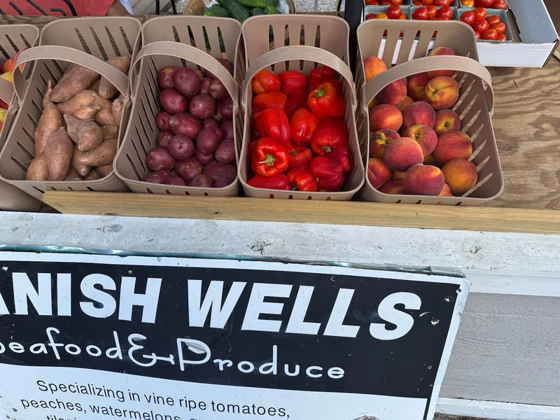 Baskets of sweet potatoes, red potatoes, peppers and peaches beside the Spanish Wells Seafood & Produce sign