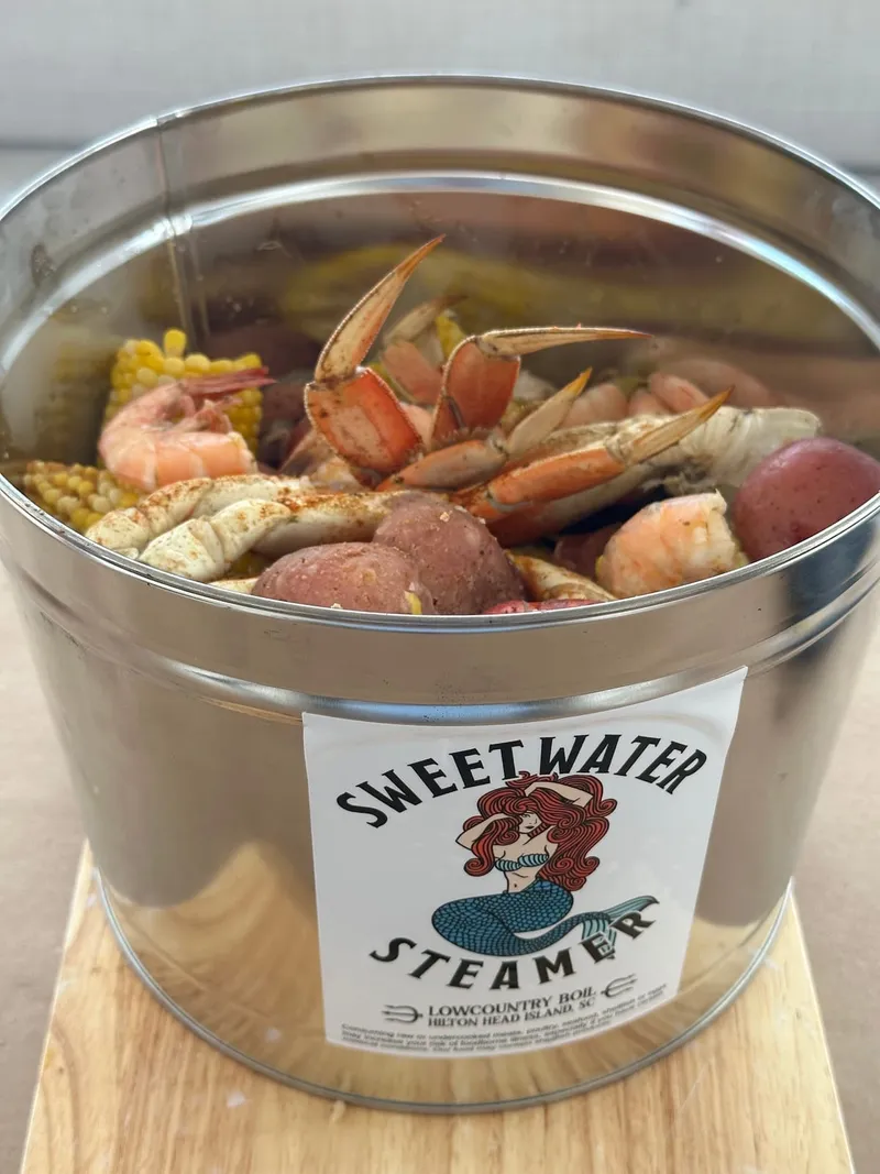 A Sweetwater Steamer souvenir bucket packed with crab legs, shrimp and potatoes for a cook-at-home Lowcountry boil