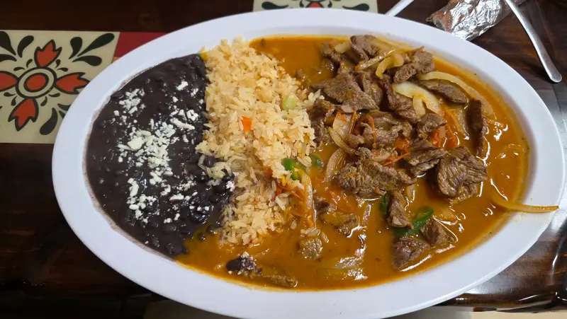 A plate of sliced steak with rice and black beans at El Potrero