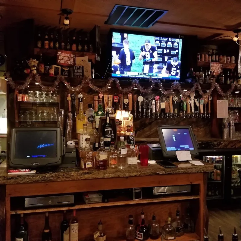 The bar at The Lodge with beer taps, a wall of bottles and a TV above the register