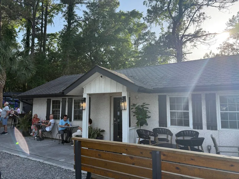 The white cottage at Tin & Tallow on Spanish Wells Road, with a covered entrance and outdoor seating