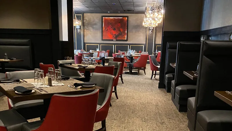 The dining room at WiseGuys with dark leather booths, red chairs and a chandelier