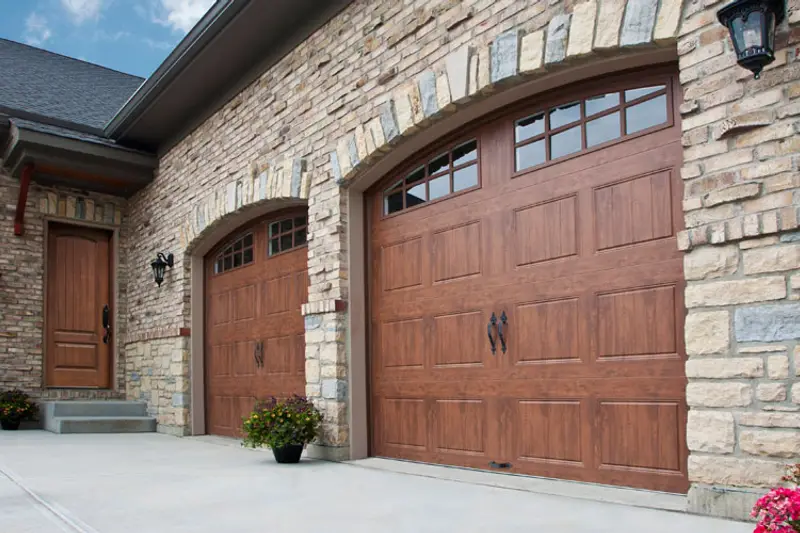 Arched wooden carriage-style garage doors on a stone house