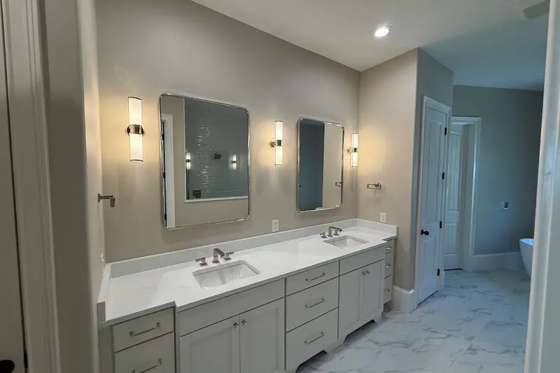 A remodeled bathroom with a double vanity, white counter and wall-mounted mirrors