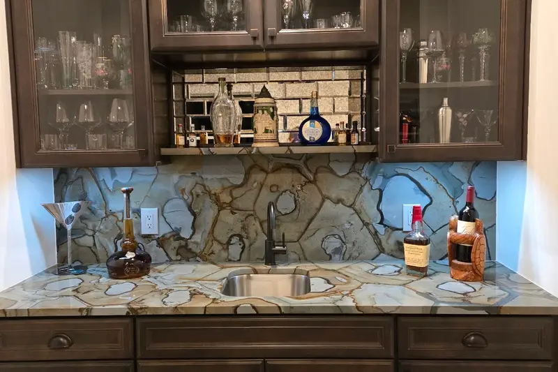 A bar with a granite countertop and a stone backsplash under dark wood cabinets