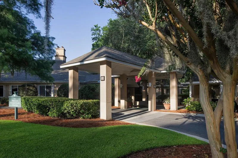 The covered entrance of The Preston Health Center under live oaks