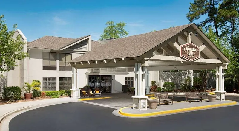 The covered entrance of the Hampton Inn Hilton Head under tall pines