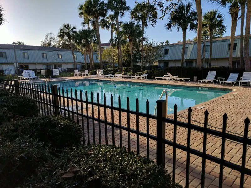 The fenced pool with the two-story villa buildings and palms behind at Hilton Head Cabanas, Forest Beach