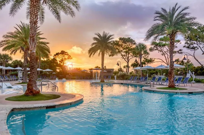 The pool at Ocean Oak Resort at sunset, with palm trees and loungers around it