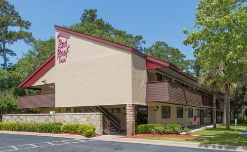 The two-story Red Roof Inn Hilton Head Island with its red-trimmed roofline among pine trees