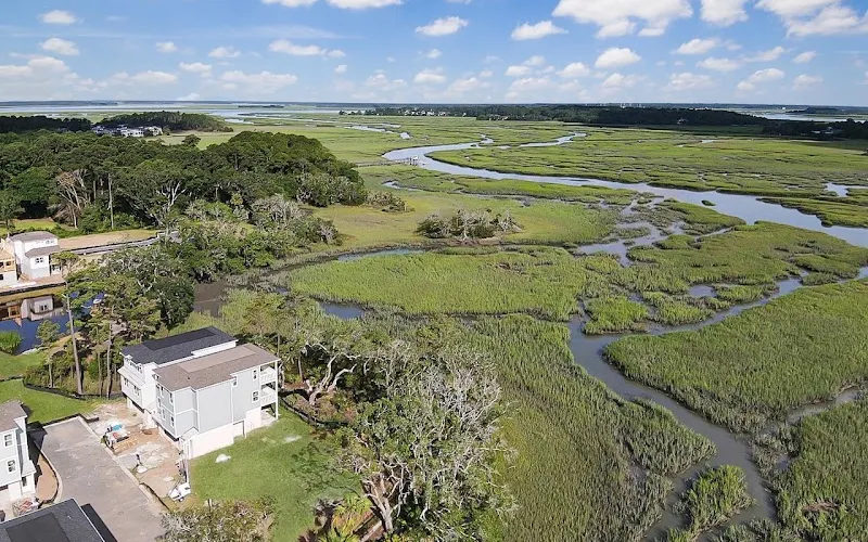 An aerial view of new houses beside a tidal marsh and creek under a blue sky