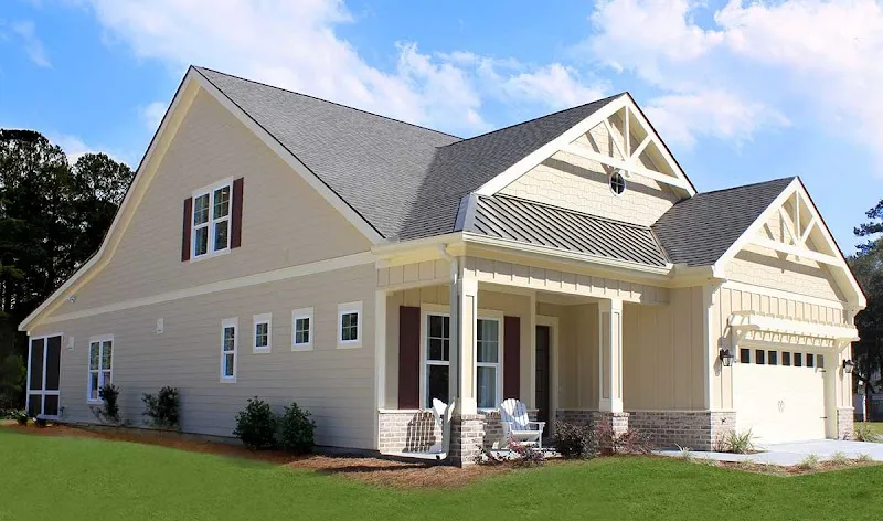 A two-story cottage-style house with a front porch, a metal-roof accent and a two-car garage