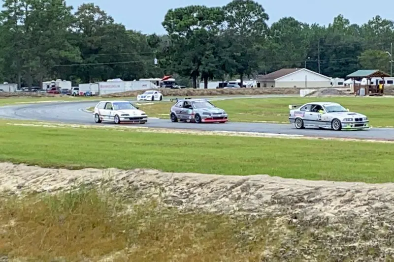 Three BMW sedans rounding a corner of the Roebling Road Raceway track during a track day