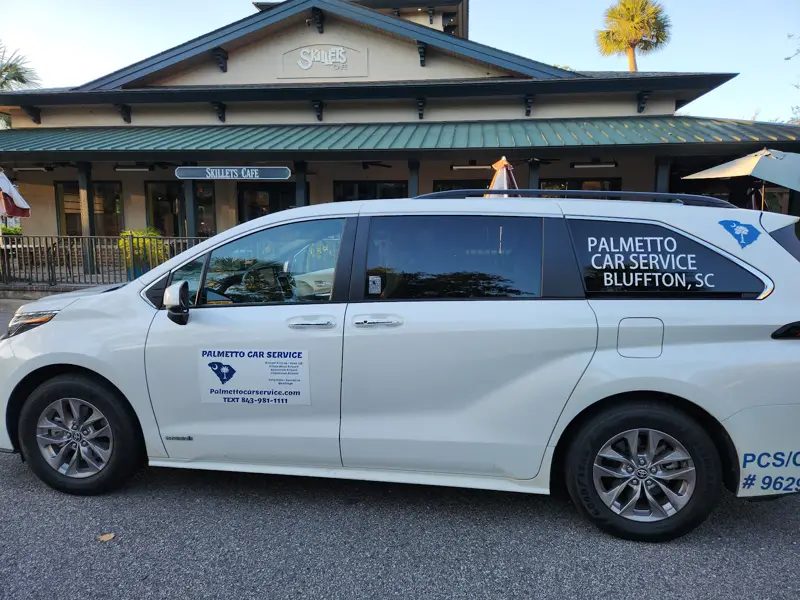 A white Palmetto Car Service minivan parked outside a Lowcountry building