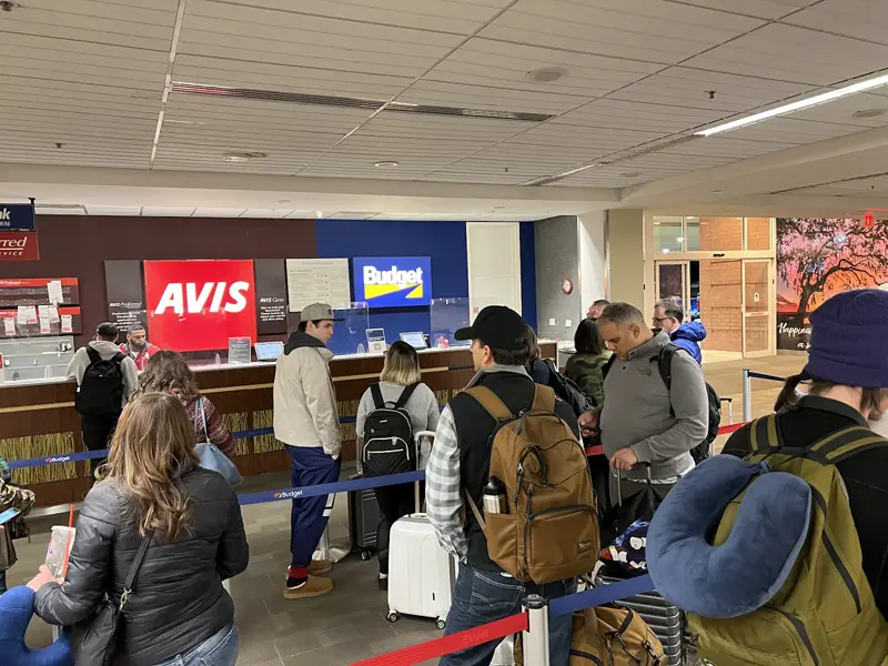 Travelers in line at the Avis and Budget counter in baggage claim at the Savannah airport