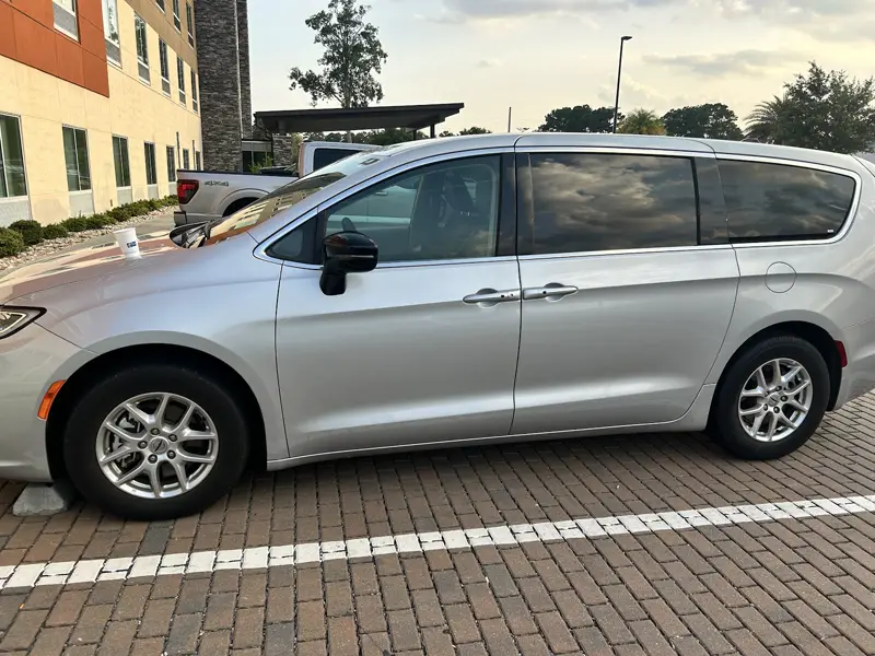 A silver minivan rental parked at the curb near the Savannah airport
