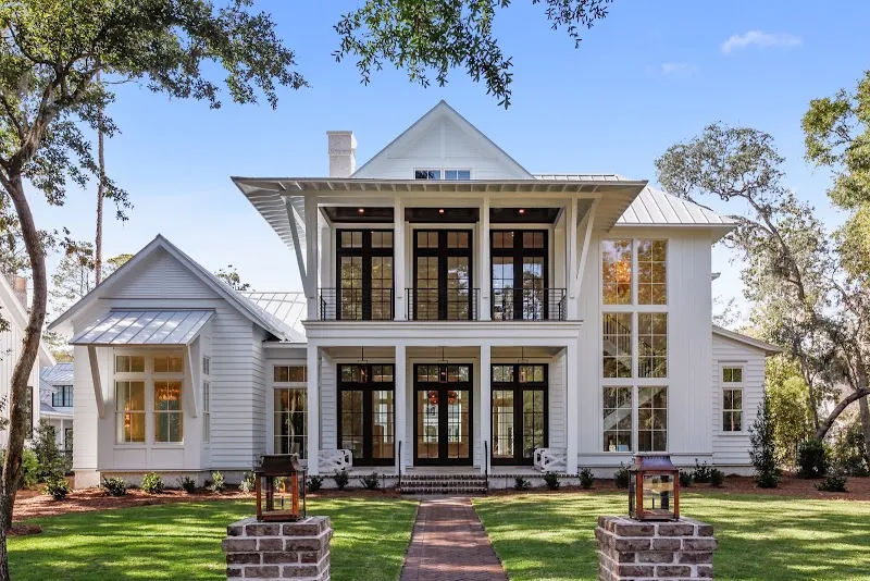 A white two-story house with double porches and a brick walk