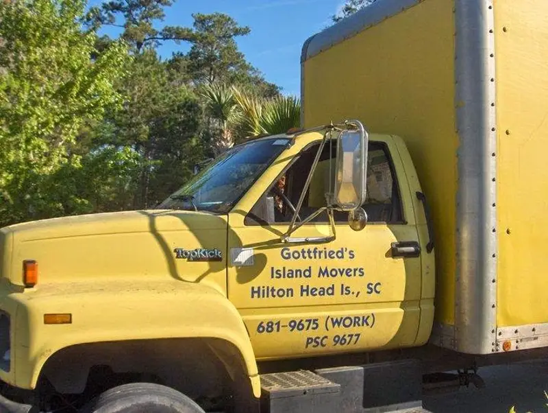 A yellow Gottfried’s Island Movers truck with its name and PSC number on the door