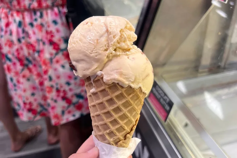 A two-scoop waffle cone held in front of the ice cream case at the Cinnamon Bear Country Store