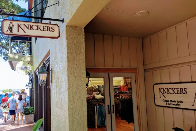 The entrance to Knickers in Harbour Town, with a hanging sign of a golfer in knickers and a wall sign for casual men’s attire